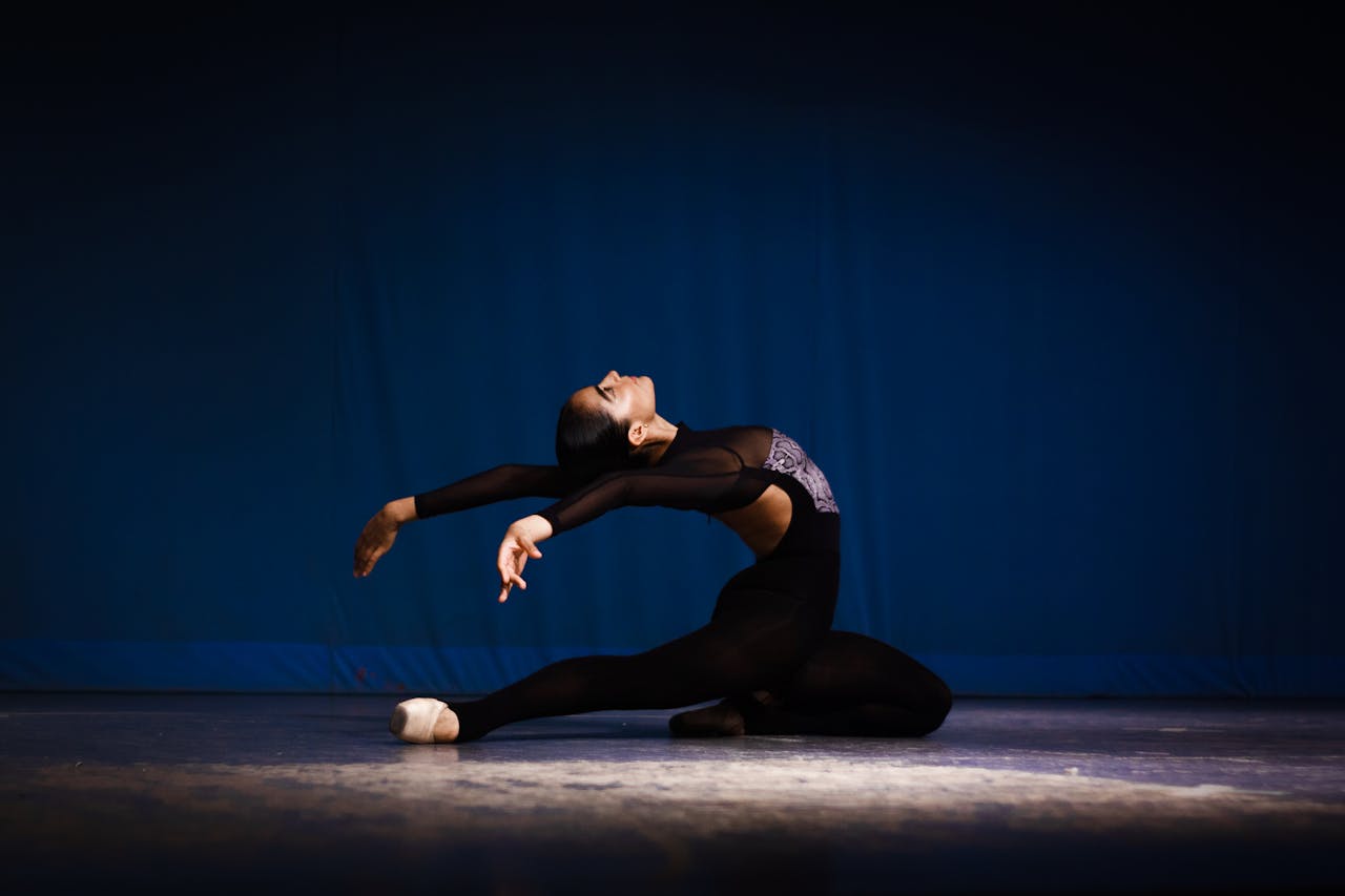 Graceful ballerina in black costume performing a dramatic dance pose.